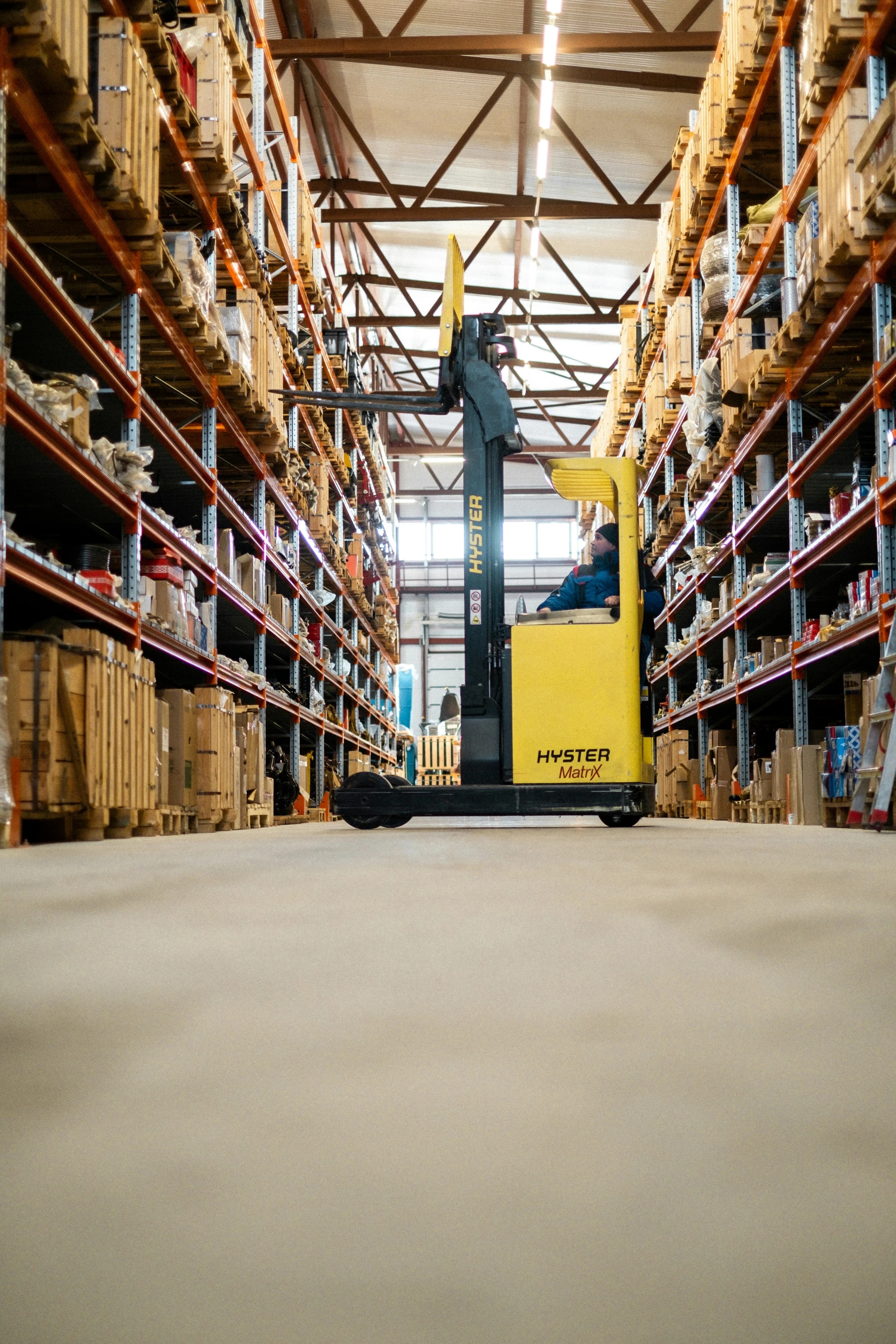Worker operating a yellow forklift in a warehouse aisle